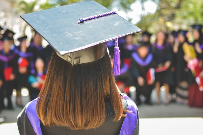 the back of a girl wearing a cap & gown at graduation